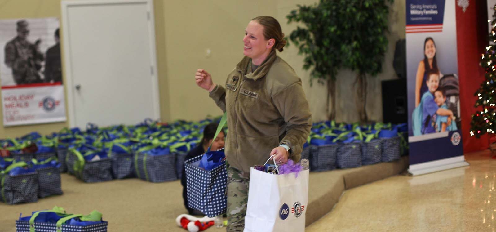 Service member carrying two bags full of food at a Holiday Meals for Military event.