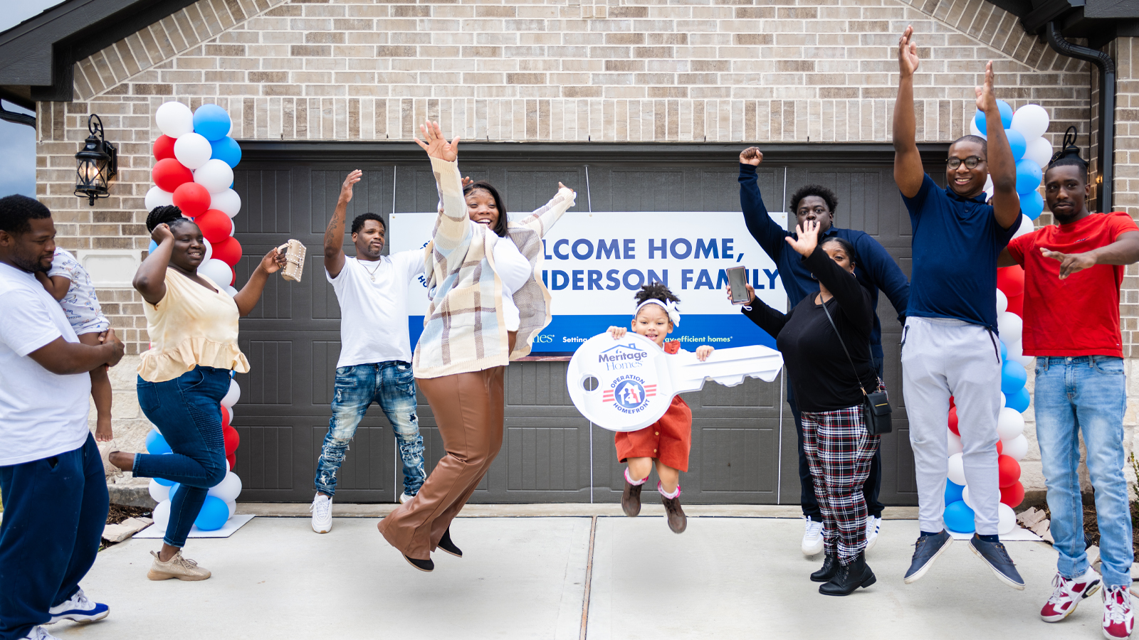 Military family jumping in front of new home